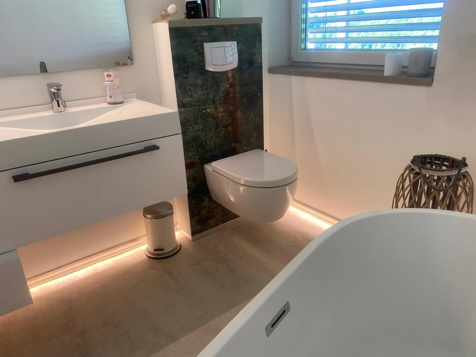 Badezimmer mit freistehender Wanne, Waschtisch und indirektem Licht